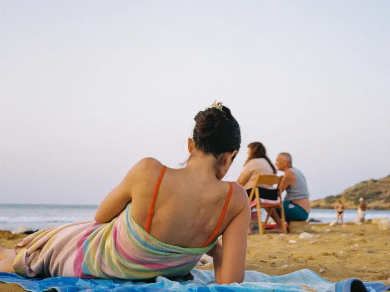Mujer de espaldas descansando sobre una toalla en la playa