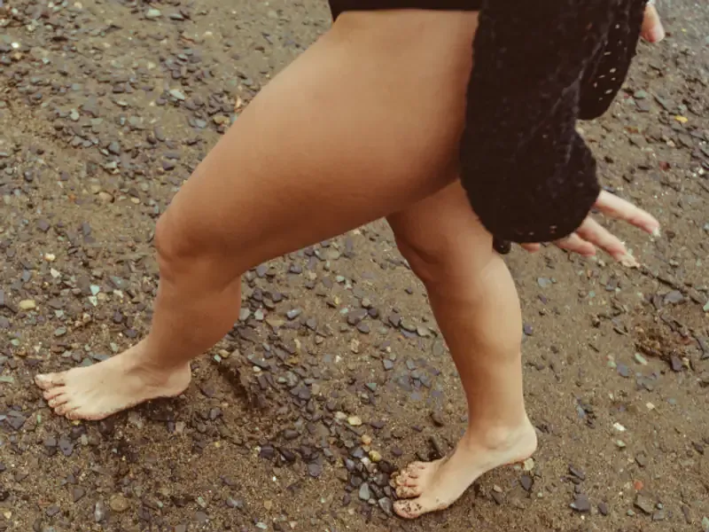 Piernas caminando descalzas sobre la arena húmeda de la orilla